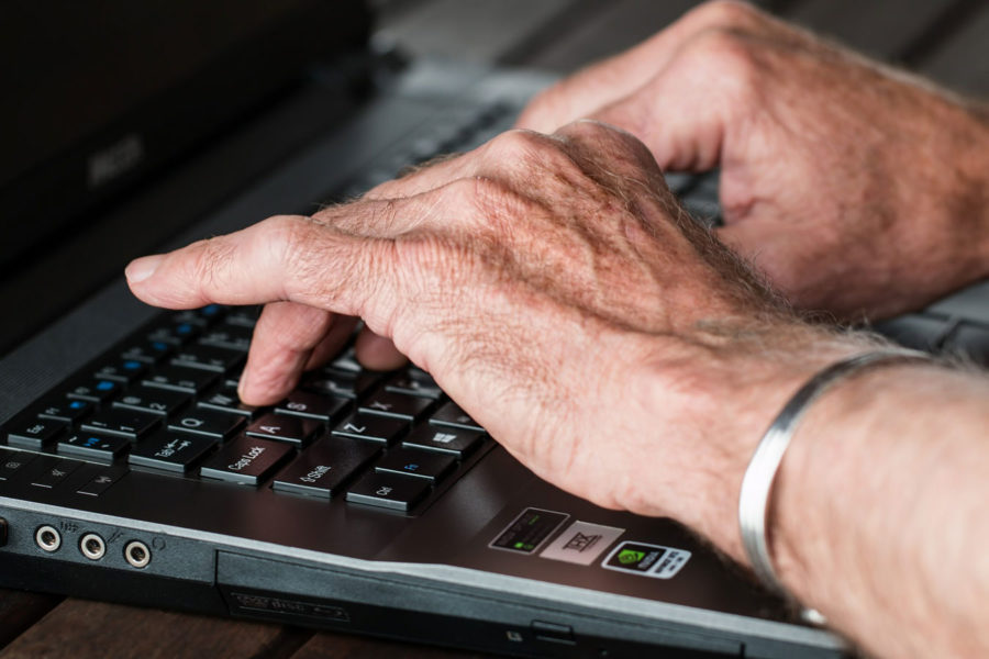 Alte Hände auf einer Tastatur